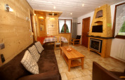 Wohnzimmer im Chalet Ronds Chetys in Frankreich mit Holzwänden, Sofa, Kamin und Essbereich.