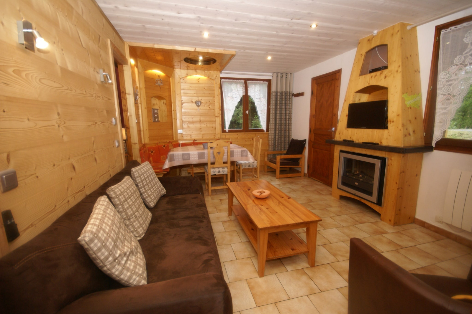 Woonkamer in chalet Ronds Chetys in Frankrijk met houten wanden, bruine bank en open haard.