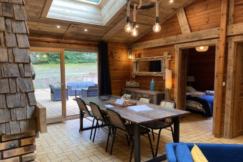 Binnenzicht van houten chalet LE FISHING LODGE met eettafel en zicht op terras in Frankrijk.