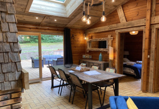 Interieur van houten chalet LE FISHING LODGE met eettafel en terrasuitzicht in Frankrijk.