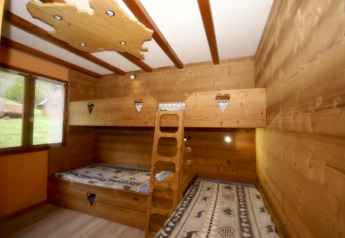 Gemütliches Zimmer mit Holzstockbetten, Herzausschnitten und Fensterblick im Chalet Ronds Chetys, Frankreich.
