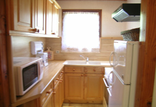 Piccola cucina con mobili in legno, forno a microonde e finestra nello chalet Ronds Chetys, Francia.