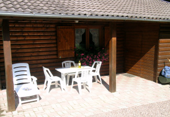 Terrasse eines Chalets namens Ronds Chetys in Frankreich mit weißen Gartenmöbeln und Blumen.