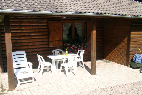Patio esterno dello chalet Ronds Chetys in Francia con mobili da giardino bianchi e fiori rosa.