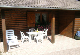 Patio esterno dello chalet Ronds Chetys in Francia con mobili da giardino bianchi e fiori rosa.