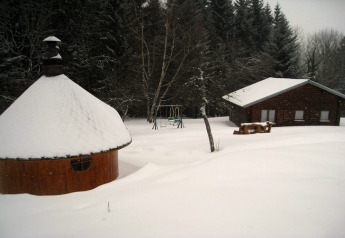 Verschneites Chalet und Grillhütte bei Ronds Chetys in Frankreich, umgeben von Bäumen und Schnee.