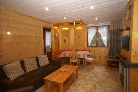Soggiorno dello chalet 'Ronds Chetys' in Francia con pareti in legno, divano e zona pranzo.