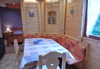 Zona pranzo in legno con panca ad angolo nel chalet «Ronds Chetys» in Francia.