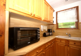 Küche im Chalet Ronds Chetys in Frankreich mit Toaster, Kaffeemaschine und Holzschränken.