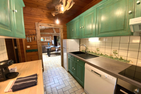 Cucina in legno di LE FISHING LODGE, Francia, con armadi verdi e zona pranzo visibile in fondo.