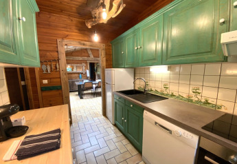 Houten keuken in LE FISHING LODGE chalet in Frankrijk, groene kasten en zicht op de eetkamer achteraan.