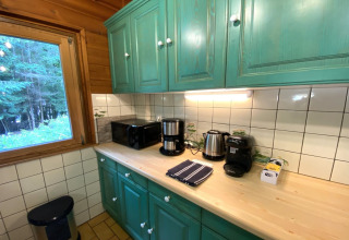 Kitchen at LE FISHING LODGE wooden chalet in France featuring green cabinets and a woodland view.