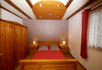 Schlafzimmer im Chalet 'Ronds Chetys' in Frankreich mit Holzmöbeln, Doppelbett und Nachttischlampen.