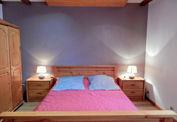 Schlafzimmer im Chalet «Ronds Chetys» in Frankreich, mit Holzmöbeln, Doppelbett und Nachttischen mit Lampen.