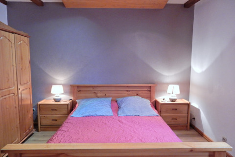Camera da letto nello chalet «Ronds Chetys» in Francia con mobili in legno, letto matrimoniale e lampade.