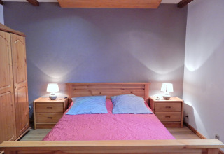 Camera da letto nello chalet «Ronds Chetys» in Francia con mobili in legno, letto matrimoniale e lampade.