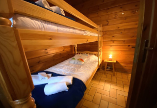 Knusse houten chaletkamer in Frankrijk met stapelbedden, zachte verlichting en welkom beddengoed.