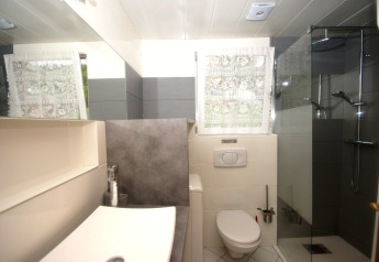 Modernes Badezimmer im Chalet Ronds Chetys, Frankreich, mit Dusche, WC und Waschbecken bei Tageslicht.