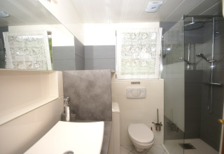Bagno moderno presso lo chalet Ronds Chetys in Francia, con doccia, wc e lavabo illuminati da luce naturale.