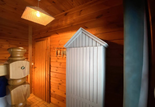 Interior view of LE FISHING LODGE wooden chalet in France with wooden walls, wardrobe, and soft lighting.