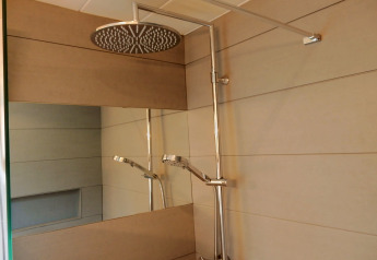 Moderne Dusche im Chalet 'Ronds Chetys' in Frankreich mit großem Duschkopf und Spiegel.