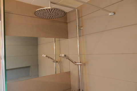 Doccia moderna con grande soffione rotondo e specchio al chalet 'Ronds Chetys' in Francia.