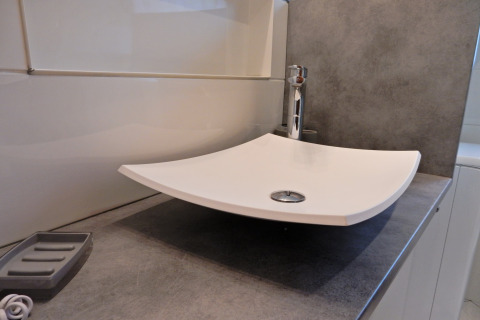 Lavandino bianco moderno e quadrato su piano grigio nel bagno dello chalet «Ronds Chetys» in Francia.