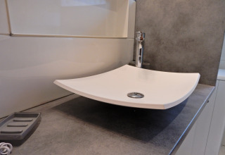 Lavandino bianco moderno e quadrato su piano grigio nel bagno dello chalet «Ronds Chetys» in Francia.