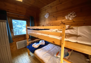 Stanza con letti a castello, pareti in legno e vista sulla neve al LE FISHING LODGE chalet in Francia.
