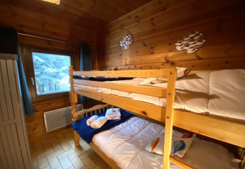 Kamer met stapelbed, houten wanden en uitzicht op besneeuwde bomen bij LE FISHING LODGE chalet in Frankrijk.
