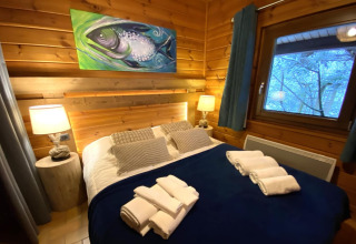 Camera da letto nello chalet LE FISHING LODGE con coperta blu e dipinto di pesce, Francia.