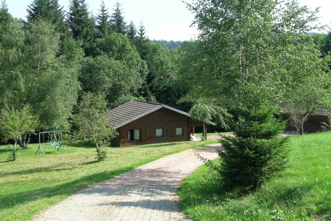 Chalet 'Ronds Chetys' in Francia, immerso nel verde con altalena, prato curato e boschi intorno.