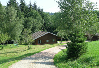 Chalet 'Ronds Chetys' in Francia, immerso nel verde con altalena, prato curato e boschi intorno.