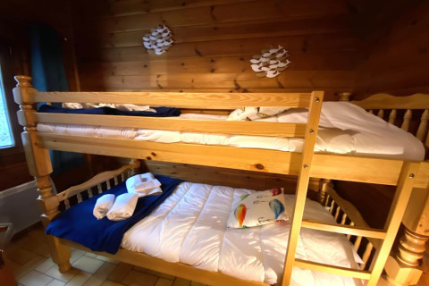Houten stapelbed bij LE FISHING LODGE met beddengoed en handdoeken in een knusse houten kamer.