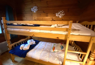 Houten stapelbed bij LE FISHING LODGE met beddengoed en handdoeken in een knusse houten kamer.