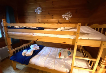 Houten stapelbed bij LE FISHING LODGE met beddengoed en handdoeken in een knusse houten kamer.