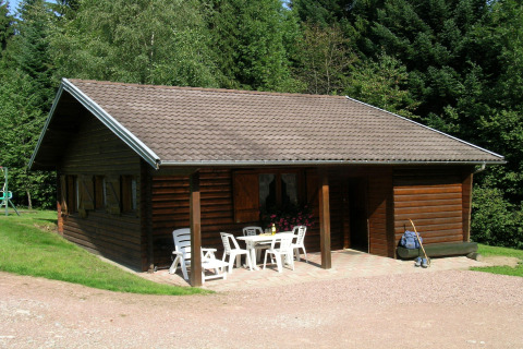 Foto esterna dello chalet Ronds Chetys con struttura in legno, sedie da giardino e foresta sullo sfondo