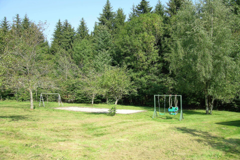 Area giochi presso lo chalet 'Ronds Chetys' in Francia con altalene, sabbiera e alberi circostanti.