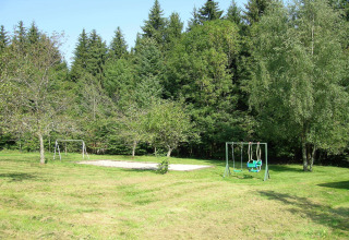 Area giochi presso lo chalet 'Ronds Chetys' in Francia con altalene, sabbiera e alberi circostanti.