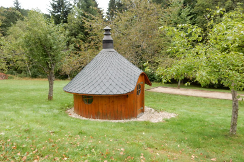 Casetta rotonda in legno dal tetto scuro, immersa nel verde presso lo chalet 'Ronds Chetys' in Francia.