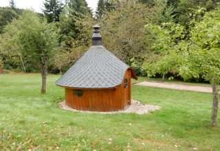 Casetta rotonda in legno dal tetto scuro, immersa nel verde presso lo chalet 'Ronds Chetys' in Francia.
