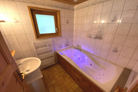 Bagno con vasca idromassaggio, piastrelle bianche e dettagli in legno al Le Fishing Lodge in Francia.