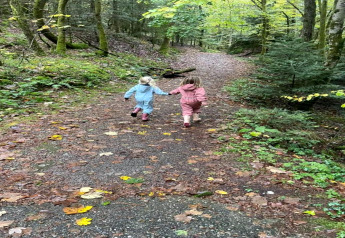 Zwei Kinder laufen Hand in Hand auf einem Waldweg nahe des Chalets 'Ronds Chetys' in Frankreich.