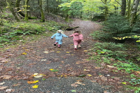 Due bambini vestiti colorati corrono mano nella mano su un sentiero vicino al chalet 'Ronds Chetys' in Francia.