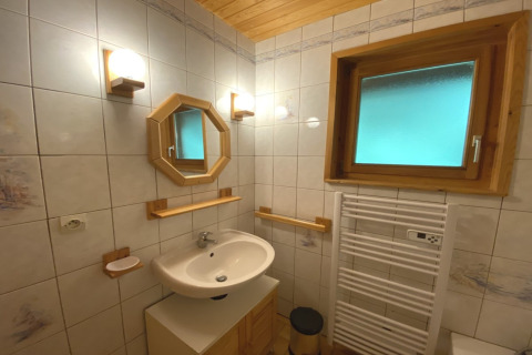 Bagno con specchio incorniciato in legno, termoarredo e finestra smerigliata in chalet francese.