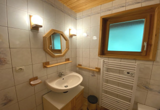 Bathroom with wooden-framed mirror, heated towel rack, and frosted window in French chalet.