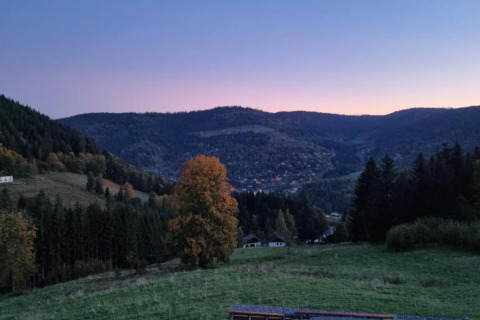 Vista dal chalet Ronds Chetys in Francia su colline verdi, una valle tranquilla e case sparse al tramonto.