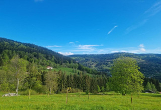 Vista delle colline verdi, alberi e una casa vicino allo chalet «Ronds Chetys» in Francia con cielo sereno.