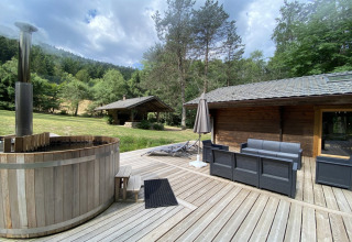 Terrazza esterna al LE FISHING LODGE in Francia con vasca nordica, divani da giardino e vista sul bosco.