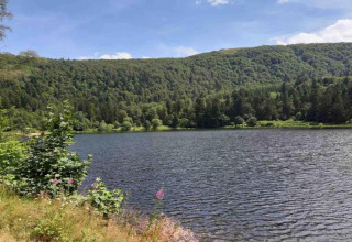Vista su un lago tranquillo e colline verdi vicino allo chalet 'Ronds Chetys' in Francia in una giornata di sole.